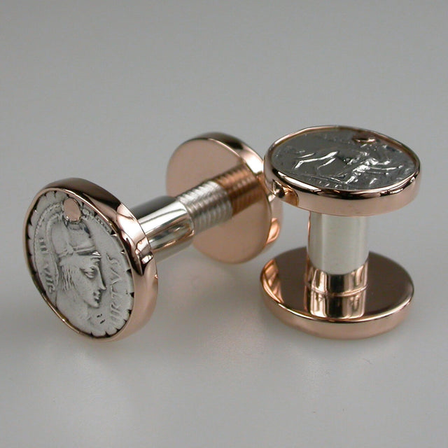 A pair of rose gold round cufflinks with silver ancient coins set on them.